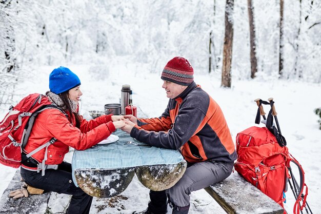 Photo happy couple  over a campfire in winter snowy forest