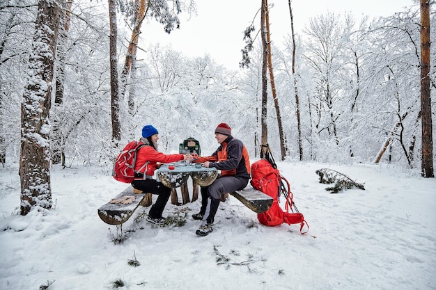 Happy couple  over a campfire in winter snowy forest