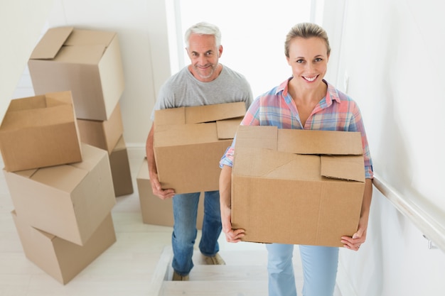 Happy couple carrying cardboard moving boxes 