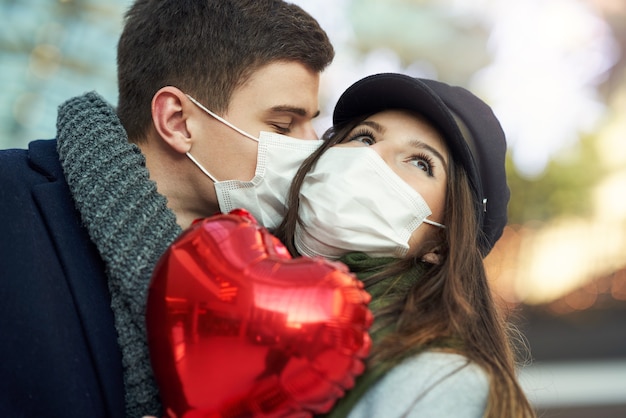 Happy couple celebrating Valentines Day in masks during covid-19 pandemic in the city