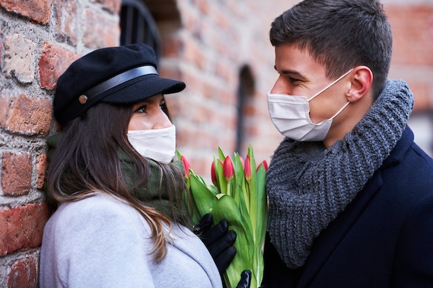 Happy couple celebrating Valentines Day in masks during covid-19 pandemic in the city