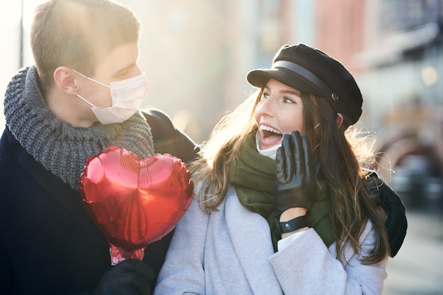 Foto coppia felice che celebra san valentino in maschera durante la pandemia di covid-19 in città