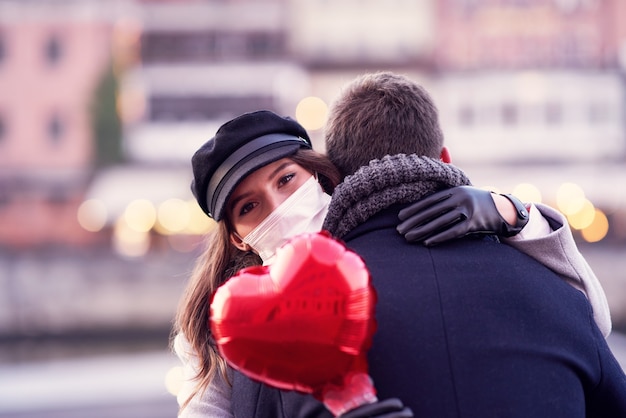 Photo happy couple celebrating valentines day in masks during covid-19 pandemic in the city