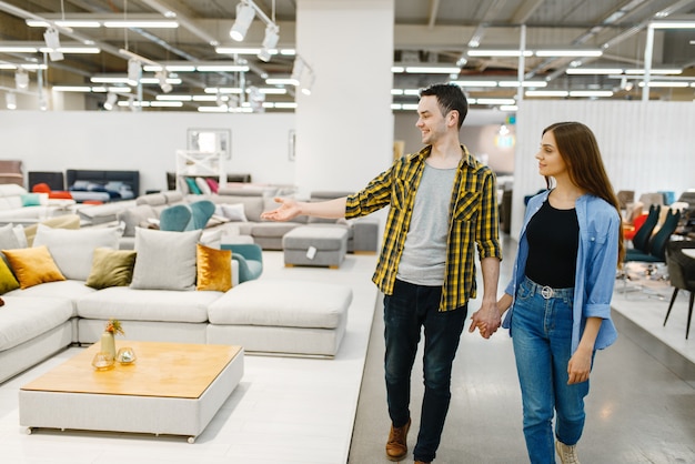 Photo happy couple choosing furniture in store showroom. man and woman looking samples for bedroom in shop, husband and wife buys goods for modern home interior