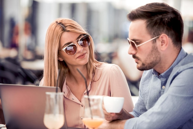 Happy couple at coffee shop looking at laptop