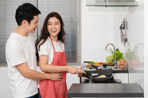 사진 행복한 커플이 집에 있는 부엌에서 요리하고 음식을 준비하는 여자를 안고 있는 남자