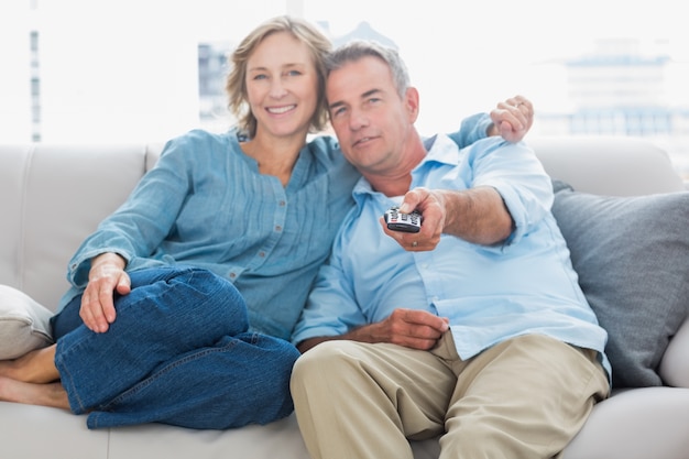 Coppie felici che stringono a sé e che si siedono sul divano che guarda tv