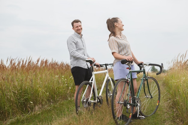 La coppia felice in bicicletta vicino al campo