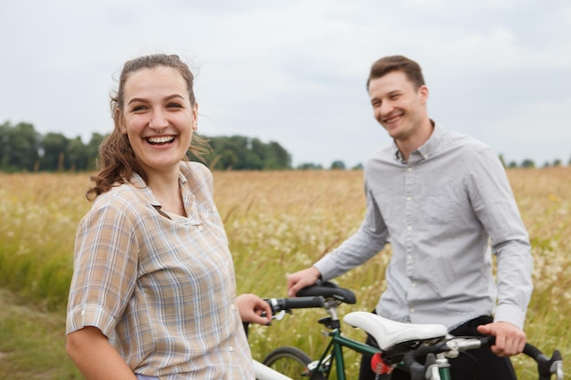 La coppia felice in bicicletta vicino al campo