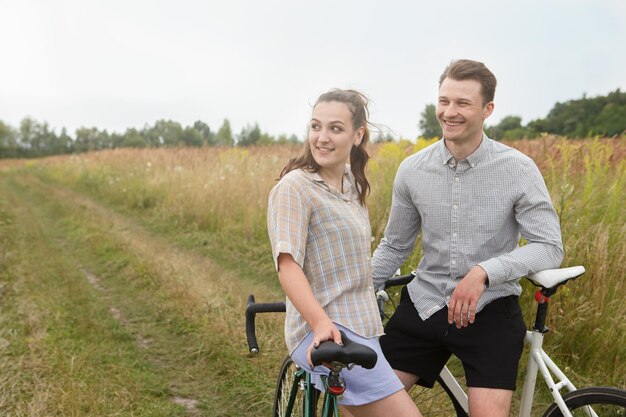 Foto la coppia felice in bicicletta vicino al campo