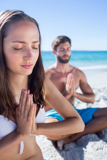 Happy couple doing yoga beside the water