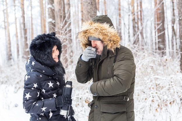 Happy couple drinking hot tea in winter forest