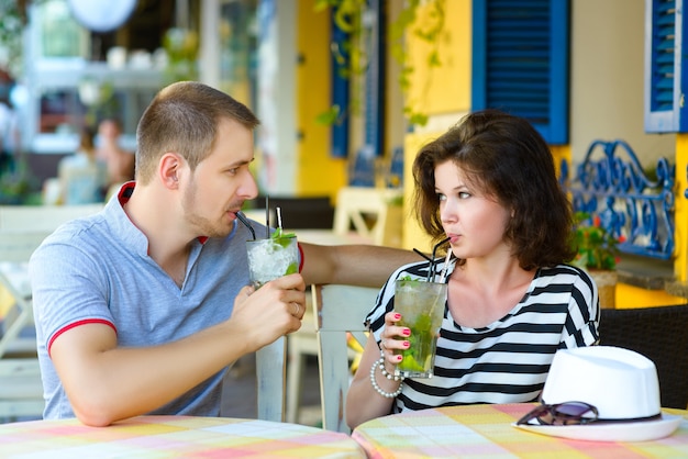 Счастливая пара, пить лимонад или мохито в уличном кафе.