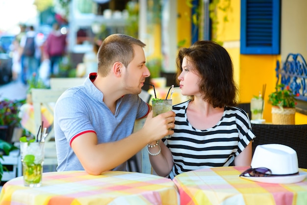 Happy couple drinking lemonade in an outside cafe.
