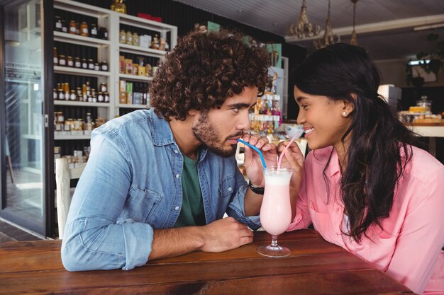 Счастливая пара пьет молочный коктейль