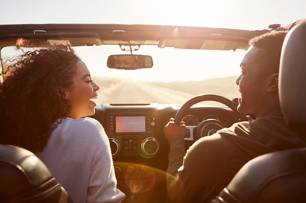 Happy couple drive looking at each other rear passenger POV