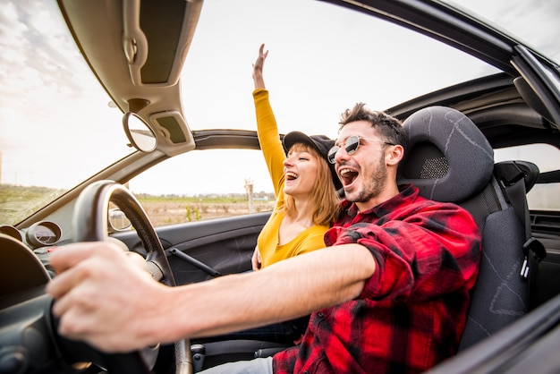 Photo happy couple driving a convertible car at sunset on the road