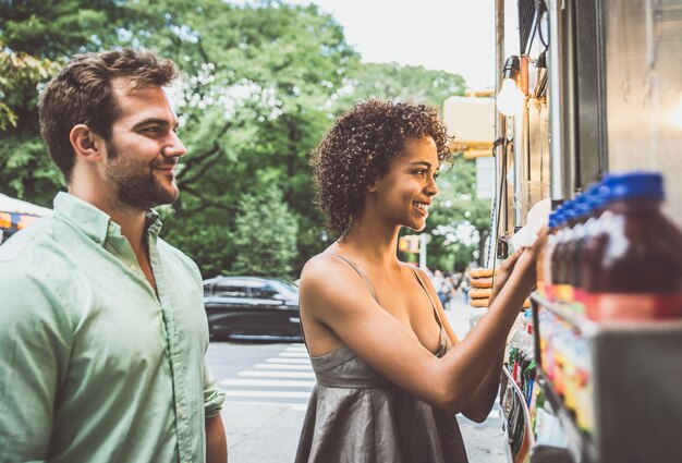 Coppie felici che mangiano i hot dog e che si divertono a new york city