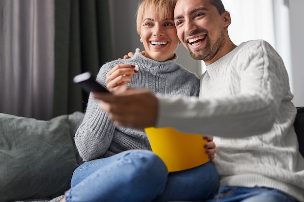 Happy couple eating popcorn and watching TV