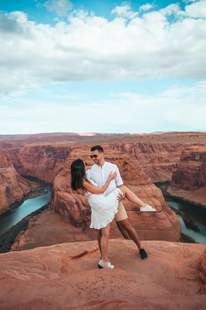 Happy couple on the edge of the cliff at Horseshoe Band Canyon in Paje Arizona Adventure and tourism concept Beautiful nature in USA