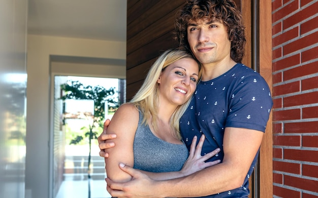 Happy couple embraced at the entrance of their new house