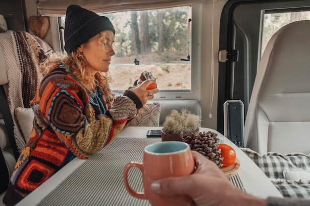 Счастливая пара наслаждается временем, пьющим чай в фургоне-фургоне Кочевой образ жизни, туристы, люди, отдыхающие, развлекательная деятельность в автодоме, аренда транспорта для отдыха, вид на парк на открытом воздухе