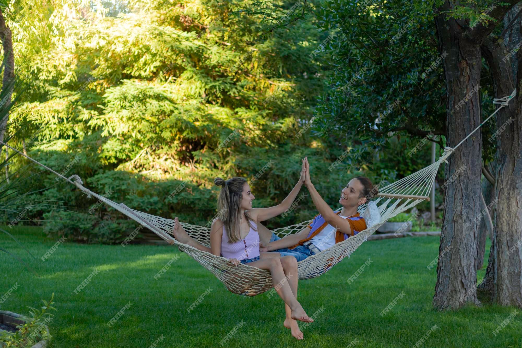 Ver weg Aantrekkingskracht cap Premium Photo | Happy couple enjoying the time relaxing in the hammock  while giving high five to each other in the garden
