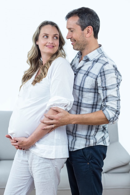 Happy couple expecting baby standing in living room