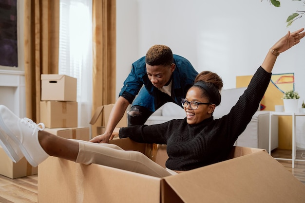 Happy couple first time home buyers having fun while unpacking\
boxes of laughter on moving day