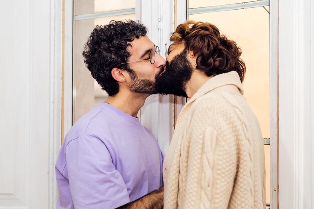 Happy couple of gay men kissing at home