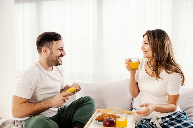 A happy couple having breakfast in the bed at their cozy home