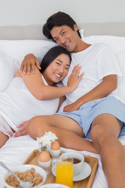 Photo happy couple having breakfast in bed