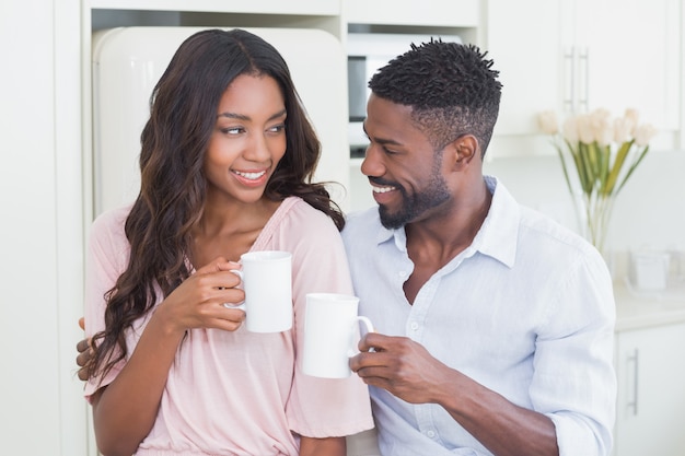 Happy couple having coffee together at home in the kitchen