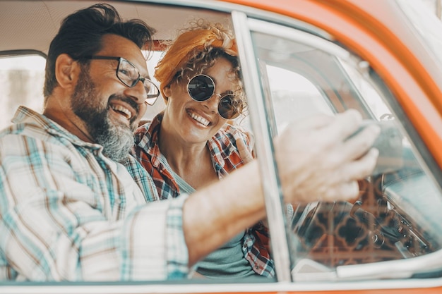 Coppia felice che si diverte all'interno di un'auto durante l'avventura di viaggio uomo e donna allegri che sorridono e ridono molto insieme persone che si godono il viaggio in veicolo in amicizia e relazione concetto di guida