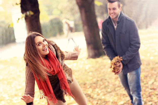 a happy couple having fun in the park in autumn