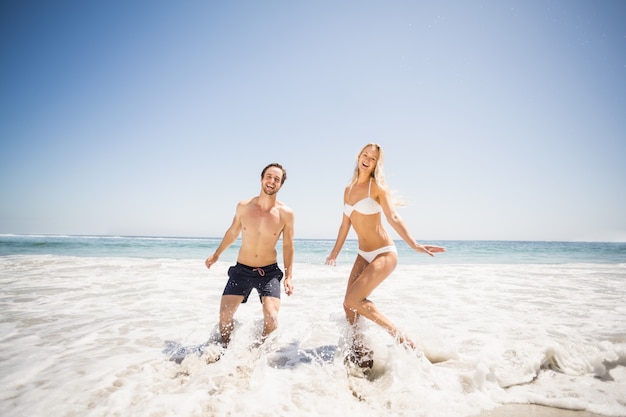 Happy couple having fun in water on shore