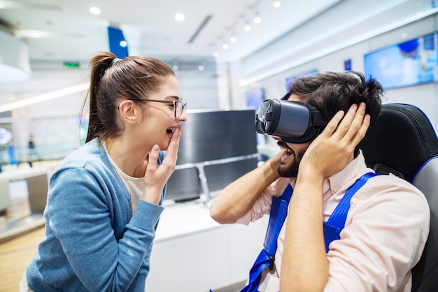 Happy couple having fun with RV goggles while boy is sitting in hair in tech store.