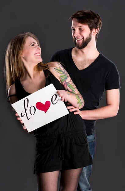 Happy couple holding board with declaration of love on a dark background