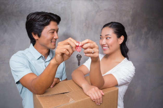 Happy couple holding house key and leaning on moving box