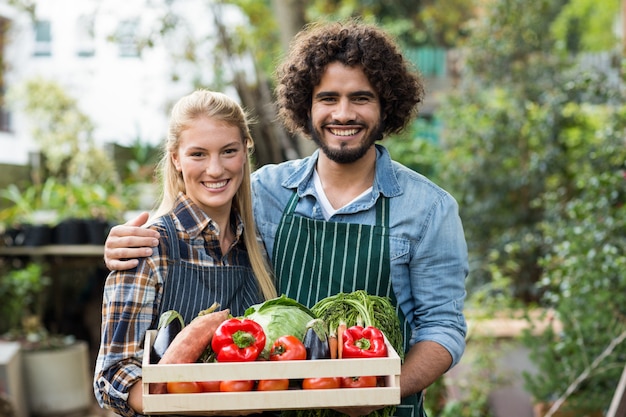 Happy couple holding vegetables crate