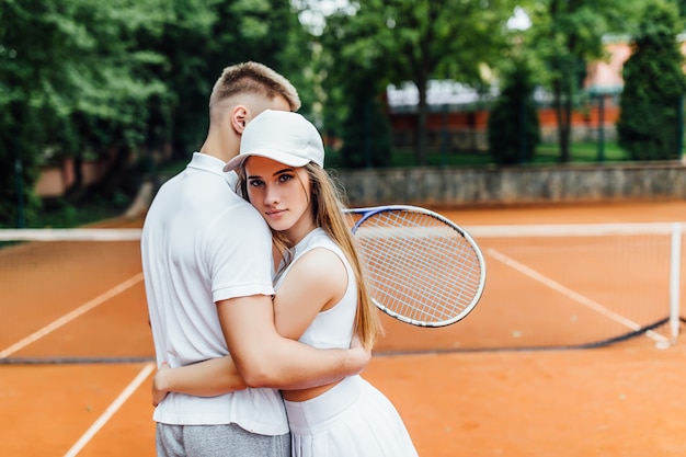 Happy couple hugging after tennis playing,training outdoors together