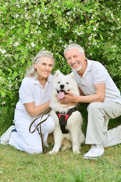 Happy couple hugging dog in spring park