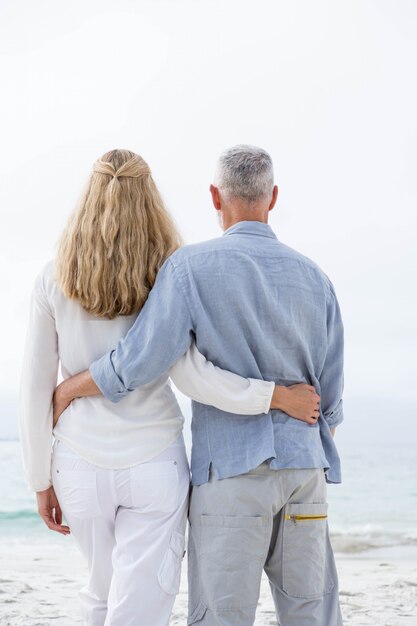 Happy couple hugging each other and looking at the sea