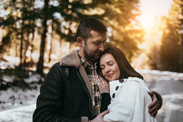 Happy couple hugginng and smiling outdoors in snowy park Selective focus