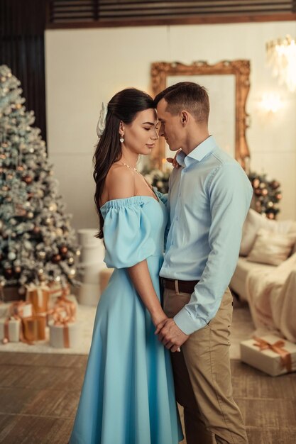 Happy couple husband and wife at home in living room near christmas tree