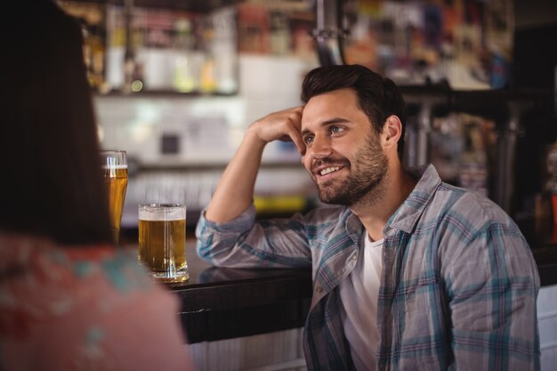 Happy couple interacting while having beer at counter