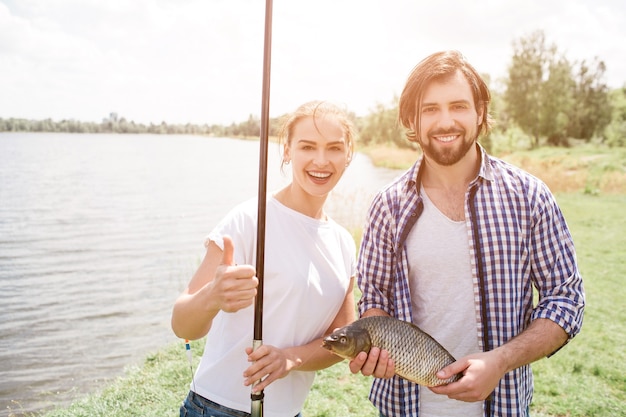 Happy couple is standing at river shroe and smiling