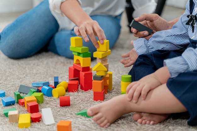 幸せなカップルとリビング ルームでカラフルなブロックのおもちゃを遊んでいる子供。家族のライフ スタイルと休日の家での一体感。