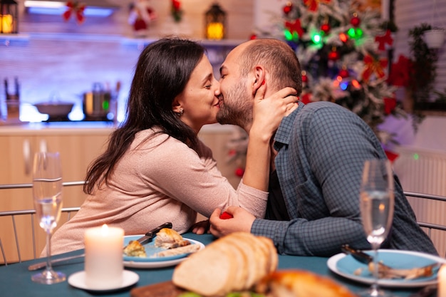 結婚の提案の後、クリスマスのキッチンでキスする幸せなカップル