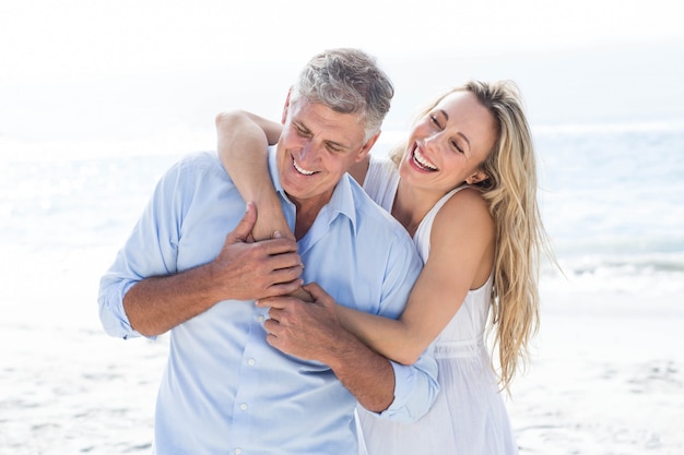 Happy couple laughing together at the beach